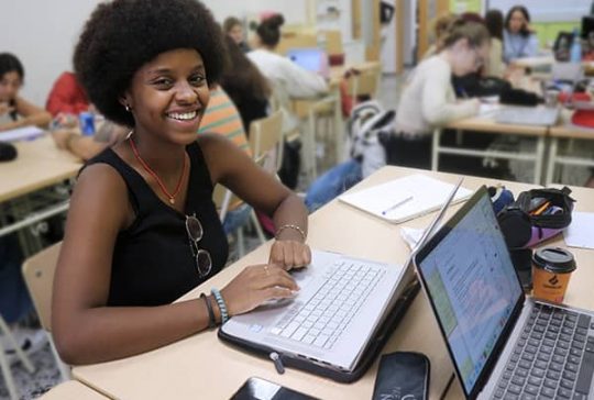 Alumna de Educación Infantil de ÍNTER realizando trabajo en aula con el ordenador portátil.